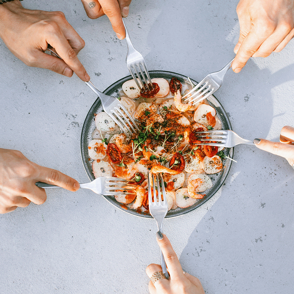 Assiette de champignons et tomates partagées par plusieurs personnes